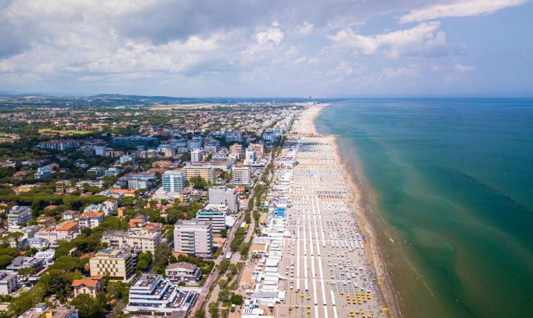 Vista aerea di una spiaggia affollata con ombrelloni colorati.