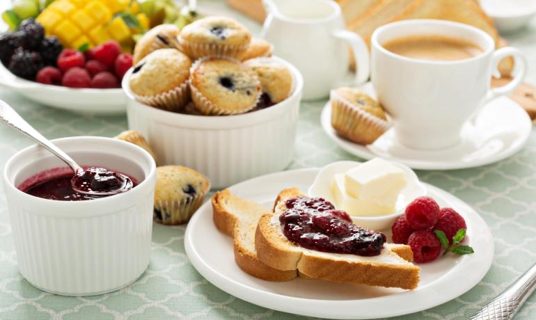 Colazione con pane, marmellata, muffin e frutta fresca.